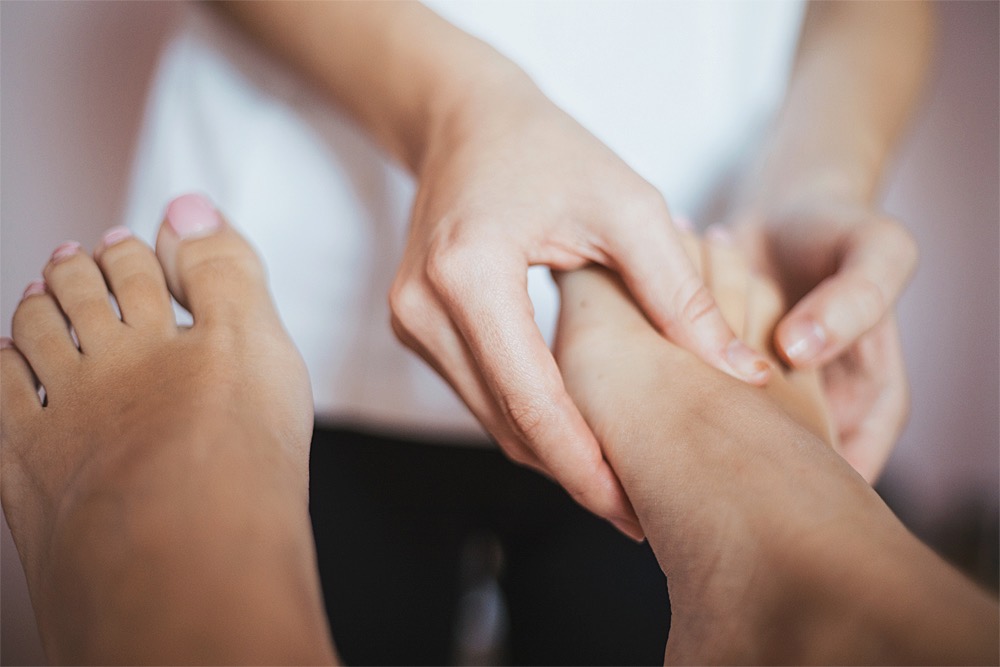 Fußreflexzonenmassage: Behandlung mit Daumen am Fußrücken